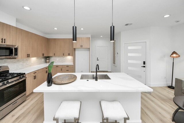 9026 Scott St, Houston, TX 77051 - kitchen with light wood-type flooring, visible vents, appliances with stainless steel finishes, a sink, and decorative backsplash