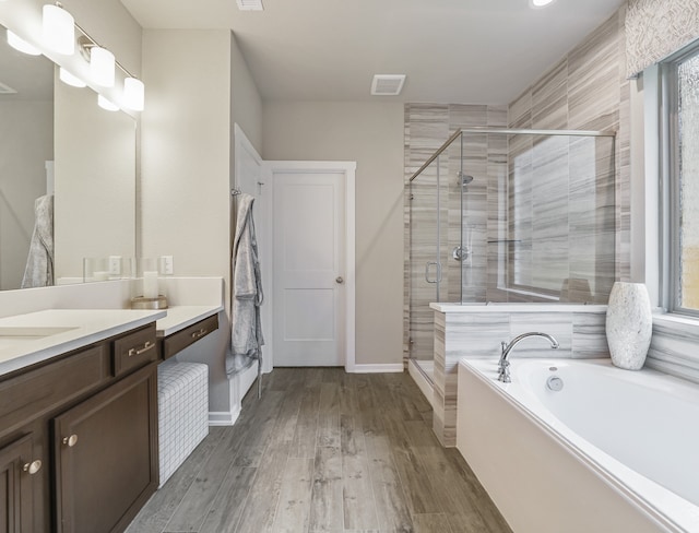 bathroom featuring a wealth of natural light, wood finished floors, vanity, a shower stall, and a bath