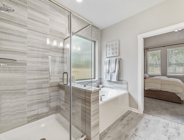 ensuite bathroom featuring a garden tub, connected bathroom, wood finished floors, baseboards, and a stall shower