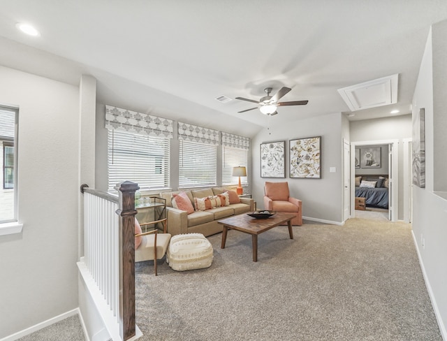 living room featuring baseboards, attic access, a ceiling fan, and light colored carpet