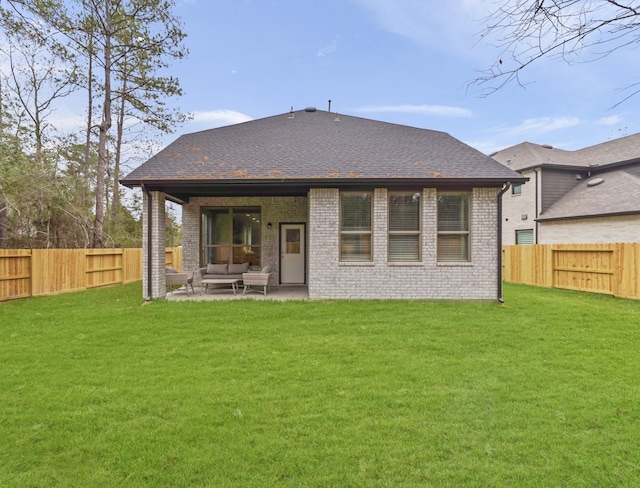 back of house with brick siding, a lawn, and a fenced backyard