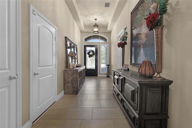 tiled entrance foyer with a raised ceiling