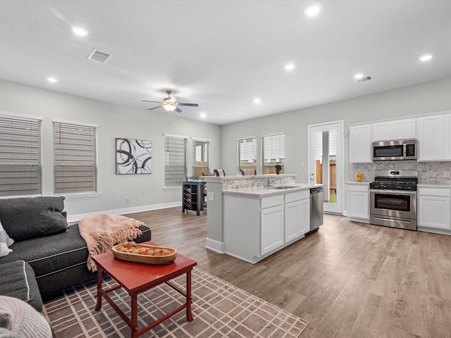 living room featuring ceiling fan, sink, and light wood-type flooring