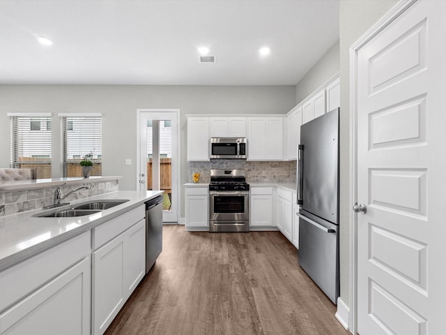 kitchen featuring appliances with stainless steel finishes, a wealth of natural light, white cabinetry, sink, and decorative backsplash