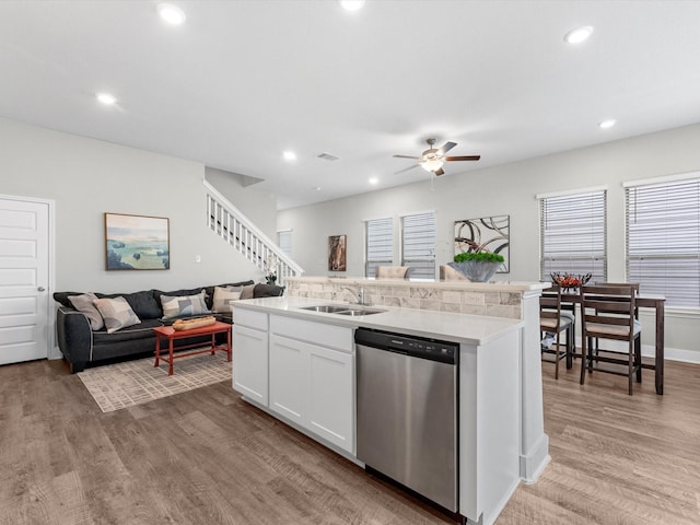 kitchen with sink, a center island with sink, stainless steel dishwasher, light hardwood / wood-style floors, and white cabinets