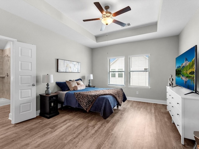 bedroom featuring ceiling fan, a tray ceiling, and light hardwood / wood-style floors