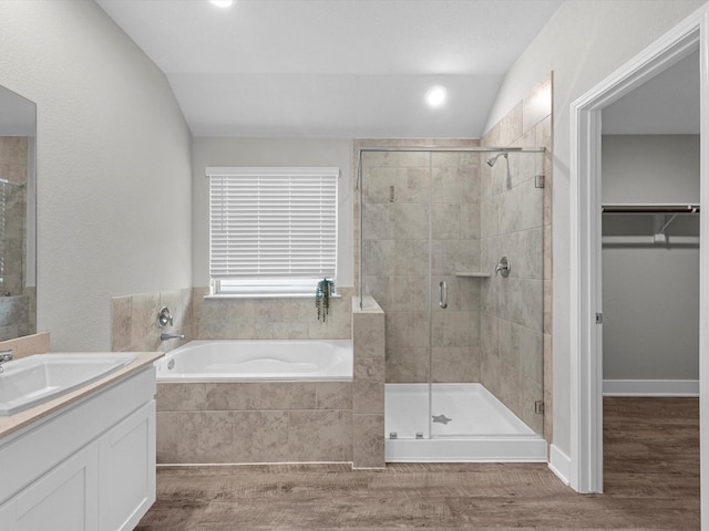 bathroom featuring hardwood / wood-style flooring, plus walk in shower, lofted ceiling, and vanity