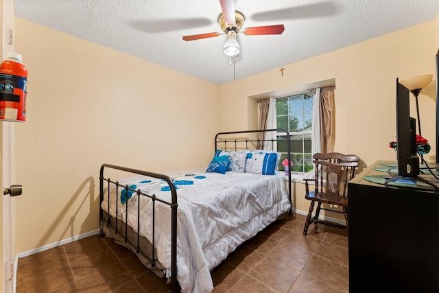 bedroom with dark tile patterned floors, ceiling fan, and a textured ceiling