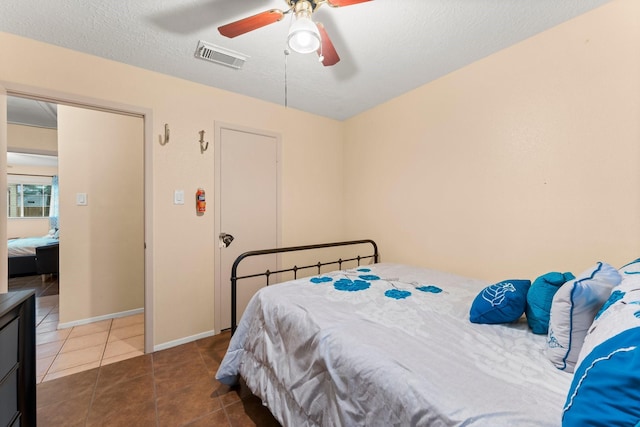 tiled bedroom featuring ceiling fan and a textured ceiling