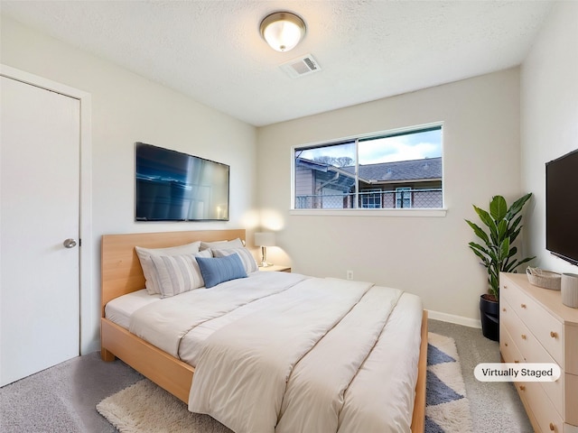 carpeted bedroom featuring baseboards, visible vents, and a textured ceiling