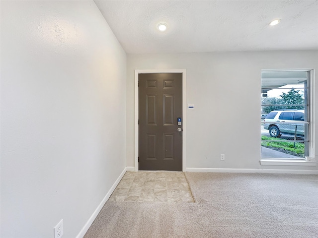 foyer featuring light carpet, baseboards, a textured ceiling, and recessed lighting