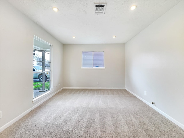 carpeted empty room featuring baseboards, visible vents, a textured ceiling, and recessed lighting