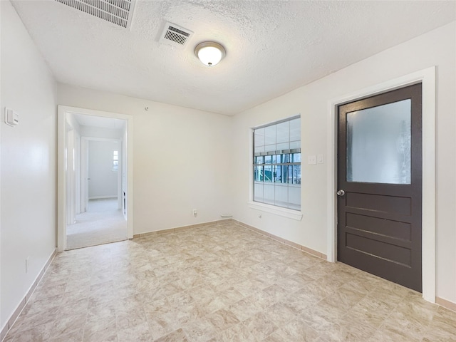 entryway with baseboards, visible vents, and a textured ceiling