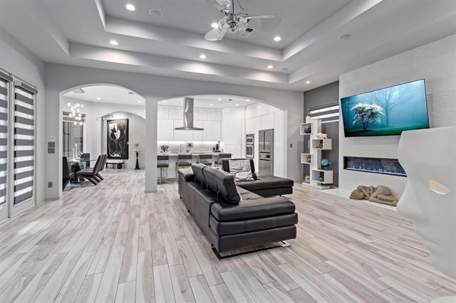 living room with a raised ceiling, ceiling fan, and light hardwood / wood-style flooring