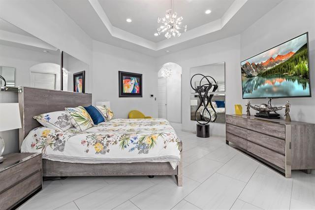 bedroom with an inviting chandelier and a raised ceiling