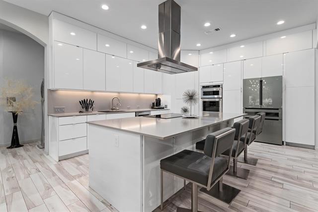 kitchen with double oven, a kitchen island, white cabinets, and island exhaust hood