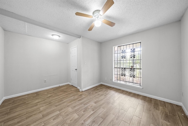 empty room with a textured ceiling, light wood finished floors, a ceiling fan, and baseboards