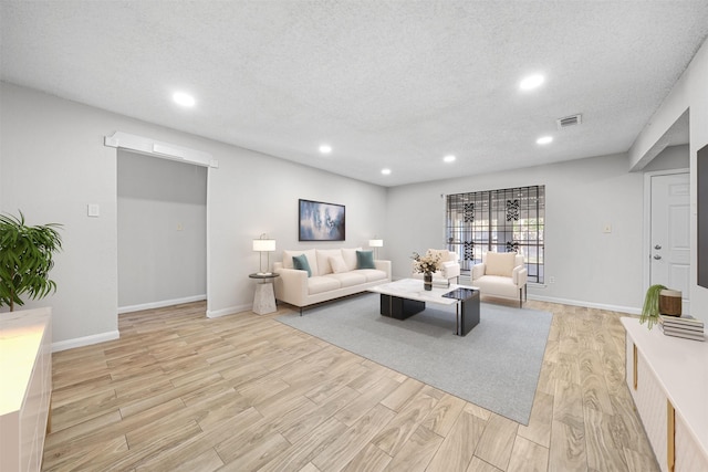 living area featuring baseboards, visible vents, a textured ceiling, light wood-type flooring, and recessed lighting