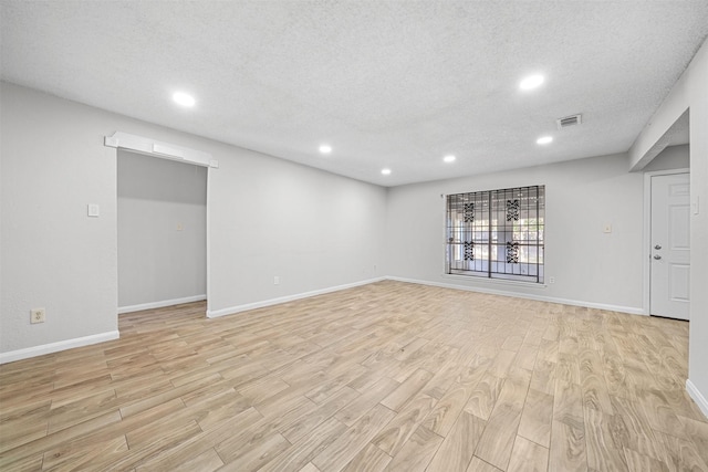 unfurnished living room with a textured ceiling, light wood-style flooring, recessed lighting, visible vents, and baseboards