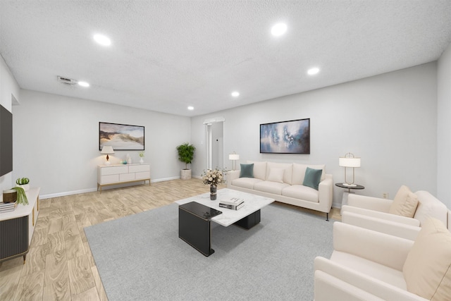 living area featuring a textured ceiling, recessed lighting, visible vents, baseboards, and light wood finished floors