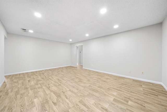 unfurnished room featuring light wood finished floors, visible vents, baseboards, a textured ceiling, and recessed lighting