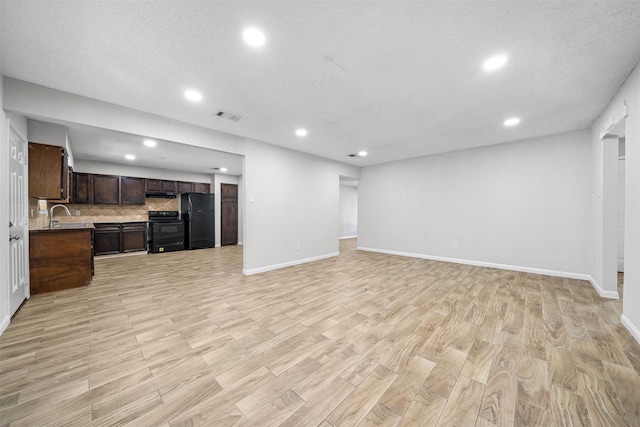 living area with light wood finished floors, baseboards, visible vents, and a textured ceiling