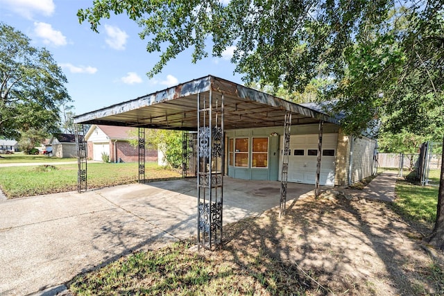 exterior space featuring a garage, concrete driveway, fence, a front lawn, and a carport