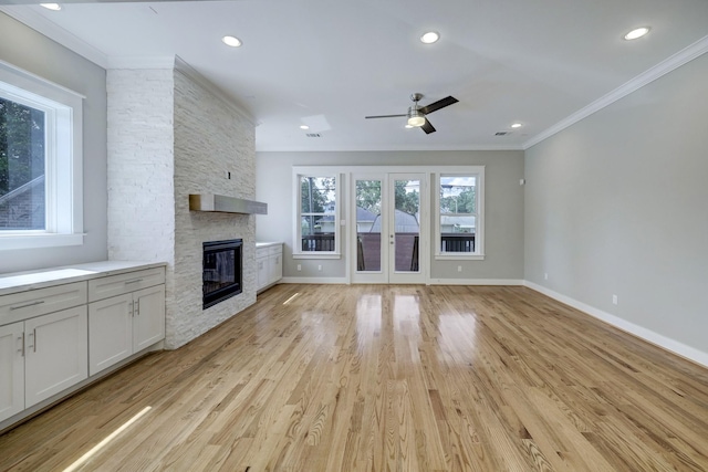 unfurnished living room with ceiling fan, ornamental molding, a fireplace, and light hardwood / wood-style floors