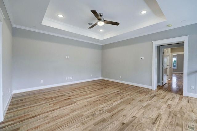 spare room with crown molding, a tray ceiling, ceiling fan, and light wood-type flooring