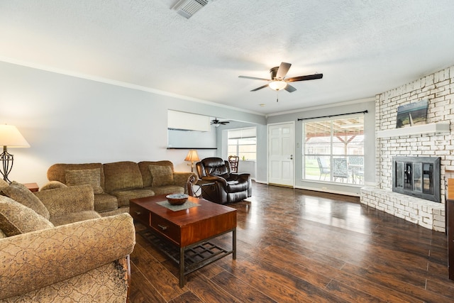 living room featuring a textured ceiling, ceiling fan, crown molding, a fireplace, and dark hardwood / wood-style flooring