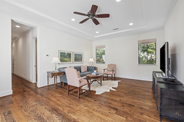 living area featuring crown molding, ceiling fan, dark hardwood / wood-style flooring, and a tray ceiling