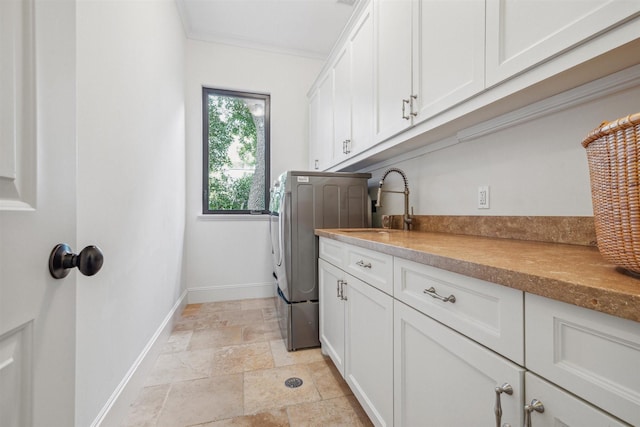 clothes washing area with crown molding, cabinets, washer / dryer, and sink