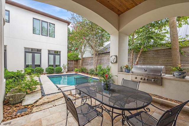 view of patio featuring a fenced in pool, grilling area, and exterior kitchen