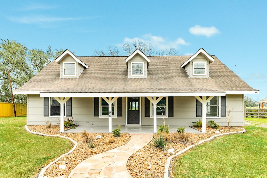 cape cod house with covered porch and a front yard