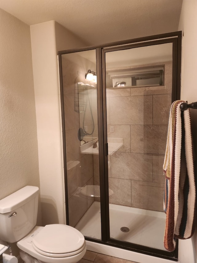 bathroom with tile patterned flooring, a shower with shower door, and toilet