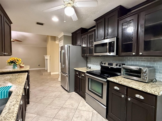 kitchen with dark brown cabinetry, light tile patterned floors, ceiling fan, stainless steel appliances, and backsplash