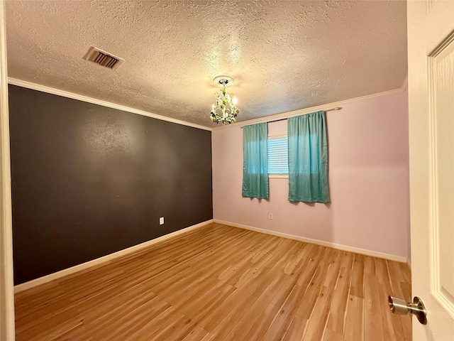 spare room with hardwood / wood-style flooring, ornamental molding, an inviting chandelier, and a textured ceiling