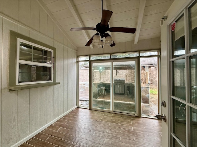 unfurnished sunroom featuring lofted ceiling with beams, plenty of natural light, wooden ceiling, and ceiling fan