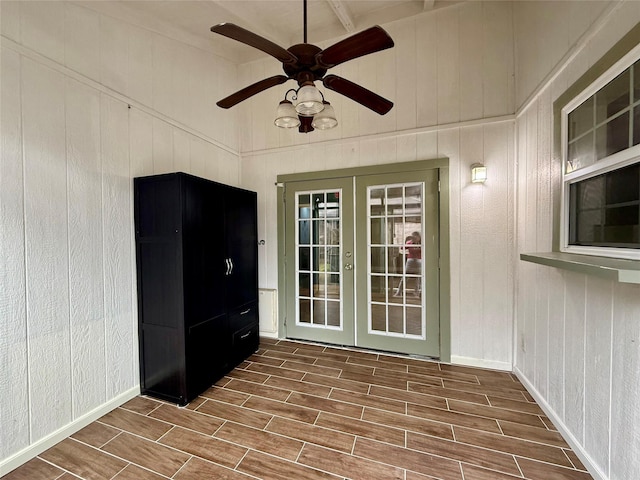 interior space featuring wood walls, ceiling fan, and french doors