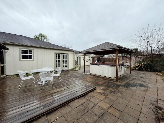 wooden deck with a hot tub, a gazebo, and french doors