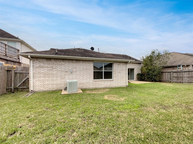 back of house featuring brick siding, fence, central AC, and a yard