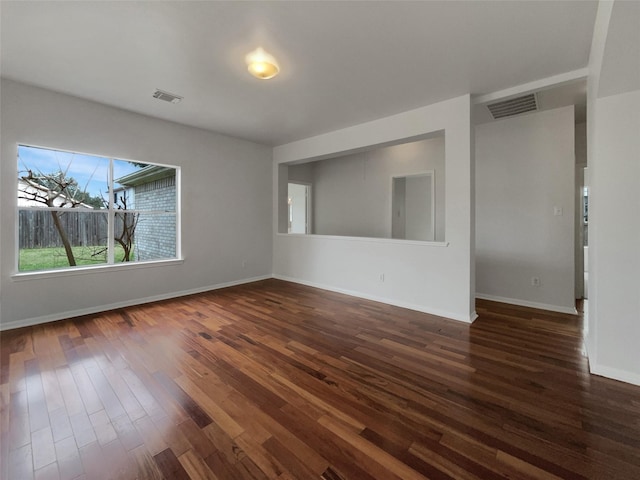 unfurnished room featuring dark wood-style flooring, visible vents, and baseboards