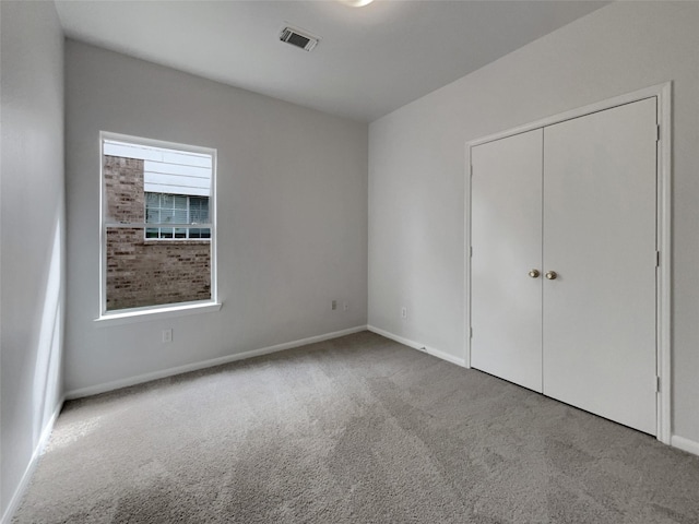 unfurnished bedroom featuring light carpet, baseboards, visible vents, and a closet