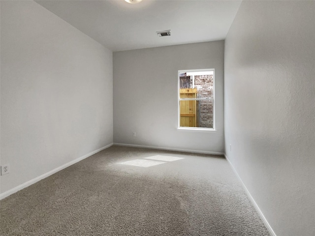 empty room featuring carpet floors, visible vents, and baseboards