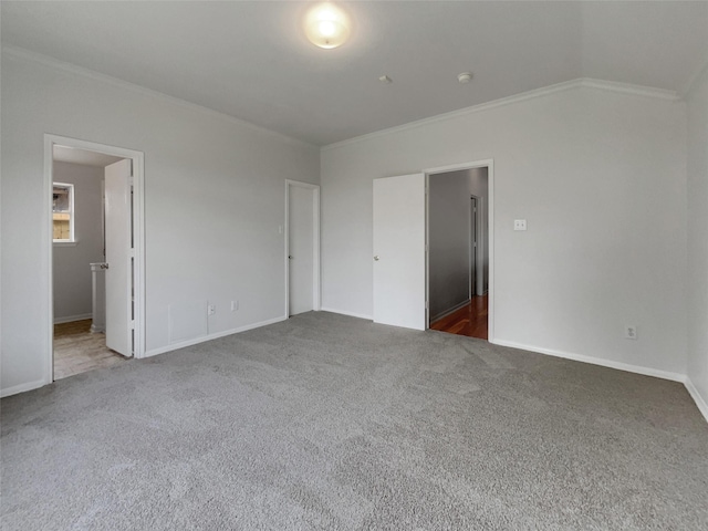 unfurnished bedroom featuring baseboards, dark carpet, lofted ceiling, and crown molding