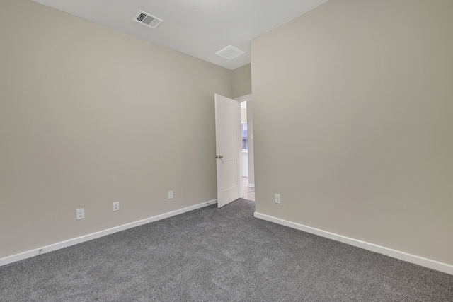 empty room featuring baseboards, visible vents, and dark carpet