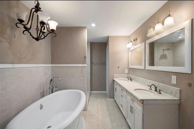 bathroom with vanity, a washtub, tile patterned floors, and tile walls