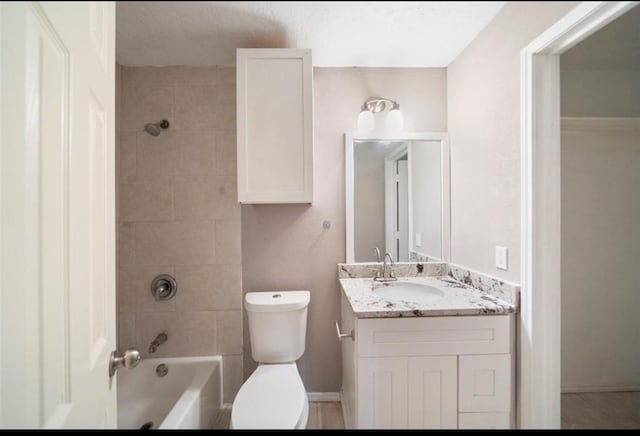 full bathroom with vanity, tiled shower / bath, and toilet