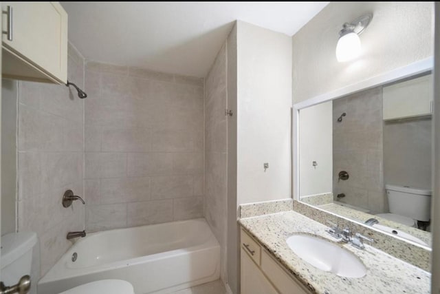 full bathroom featuring tiled shower / bath, vanity, and toilet