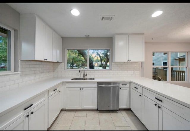 kitchen with light tile patterned flooring, sink, dishwasher, white cabinets, and backsplash